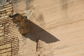 stone waterspout on the wall with bricks at alhambra spain