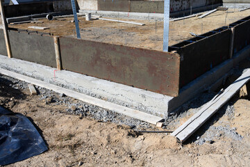 New house in beginning stage on job site, foundation dug out and wood cement forms in place, residential neighborhood housing development
