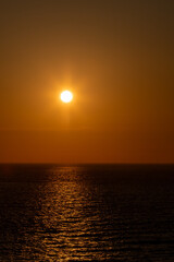 Golden sunset reflecting on calm sea with offshore wind turbines