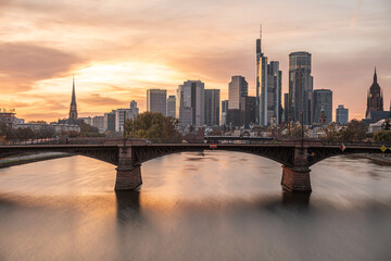 Obraz premium Frankfurt skyline reflecting in main river at sunset with bridge