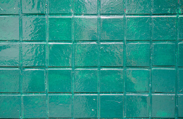 Naklejka premium Wall is covered with square tiles painted green, creating a textured surface that gives the design an artistic look, ideal for decoration,