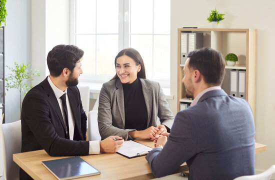 Business meeting, negotiation, client consultation around desk, engaged in discussion or meeting, agent suggesting document for couple in professional office environment, participating conversation