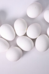 Top Down View Of Several White Chicken Eggs Scattered On A White Background. Healthy Food, Breakfast Ingredients And Cooking Concept. Vertical.