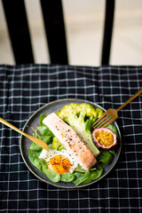 Grilled salmon fillet and fresh vegetable salad. Healthy keto food - green salad and grilled salmon on black background, space for text.
