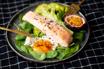 Grilled salmon fillet and fresh vegetable salad. Healthy keto food - green salad and grilled salmon on black background, space for text.