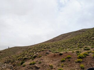 Rolling hills and vegetation in Zaouiat Ahansal, Atlas Mountains under cloudy sky