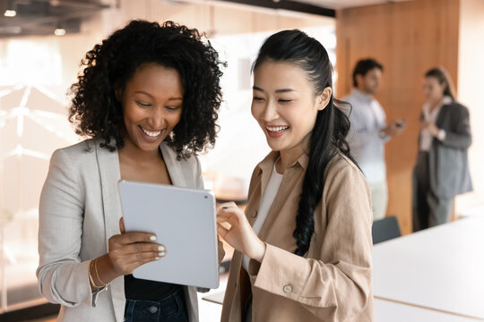 Modern tools for business success. Smiling confident young businesswomen professional executives workmates use digital tablet app to brainstorm idea pitch strategy review team project task. Copy space