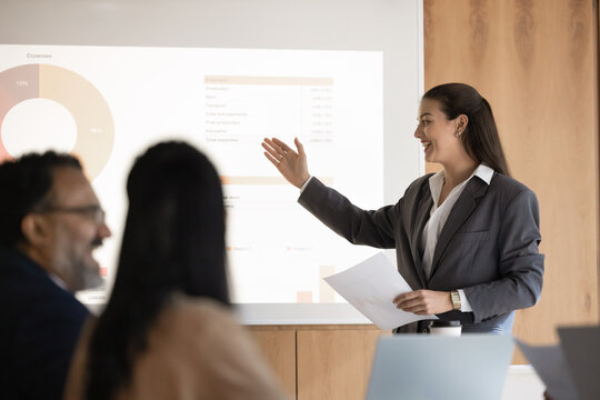 Business presentation and public speaking. Confident young businesswoman project manager executive speak at boardroom to diverse audience present statistical financial report using digital whiteboard