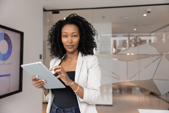 Successful career in digital workspace. Portrait confident young businesswoman social media marketer finance analyst smiling at camera holding pad to work with business data visualizations. Copy space