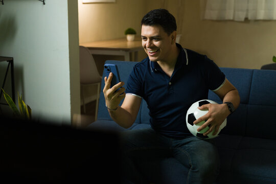 Hispanic man watching soccer and checking bet on his phone