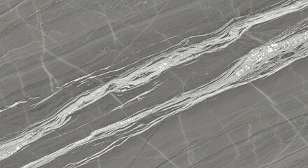 A detailed view of a polished grey marble surface with dramatic, flowing white and silver veins creating a natural abstract pattern.