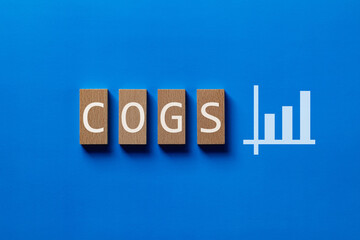 There is wood block with the word COGS. It is an abbreviation for Cost of goods sold as eye-catching image.