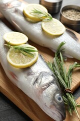 Fresh raw seabass with spices on black table, closeup. Fish and seafood delicacies