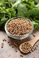 Fresh cilantro and coriander seeds on wooden table, closeup