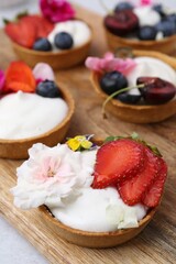 Sweet tartlets with berries and flowers on grey table, closeup. Delicious dessert