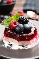 Delicious panna cotta with berries, jam and mint on table, closeup