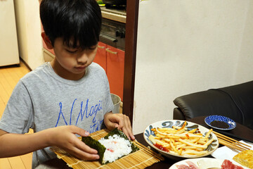 手巻き寿司の夕食のご飯を作る小学生の子供