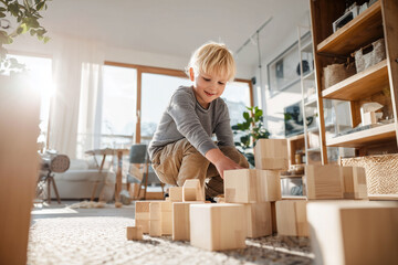 Joyful Child Engaged in Creative Play with Wooden Blocks on Cozy Carpet in Bright Living Room
