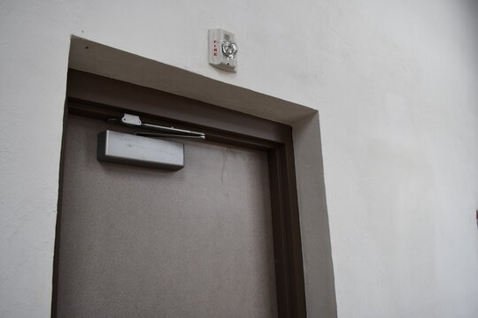 Commercial building exit door. Fire alarm strobe mounted above door. Automatic door closer installed.