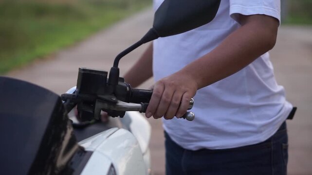 Left hand holding the handlebars for braking system at matic motorcycle