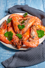 Cooked prawns decorated with green leaves resting on white plate