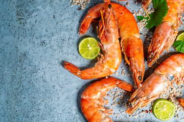 Cooked prawns with lime and coarse salt on blue background