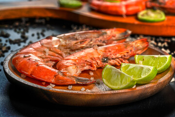 Grilled prawns with lime and coarse salt on wooden plate