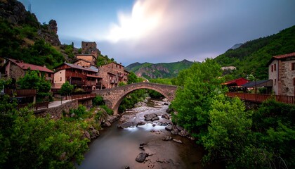 Picturesque stone village nestled beside a flowing river and an ancient stone arch bridge.