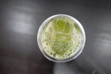 Top view of a glass filled with iced green matcha latte, a refreshing and cool beverage