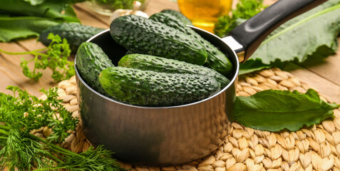 Saucepan with fresh cucumbers for preservation on table