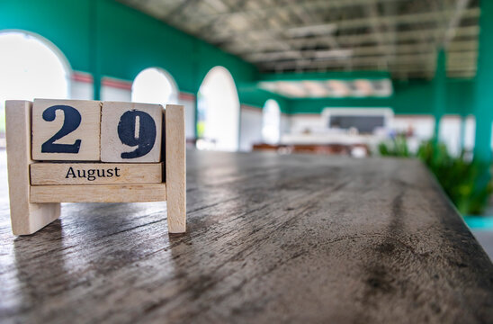 Wooden cube calendar for 29th August place on a table in a blur cafe background