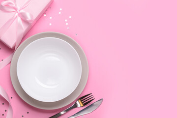 Festive table setting with present on pink background