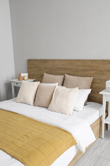 Interior of light bedroom with big bed, pillows and bedside tables