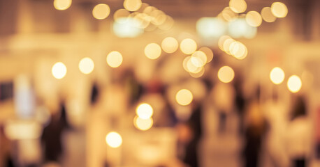 Blurred image of people indoors with a soft focus and warm bokeh lights, creating depth, intimacy, and a gentle glow in the ambient interior setting.