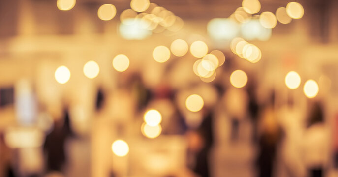 Blurred image of people indoors with a soft focus and warm bokeh lights, creating depth, intimacy, and a gentle glow in the ambient interior setting.