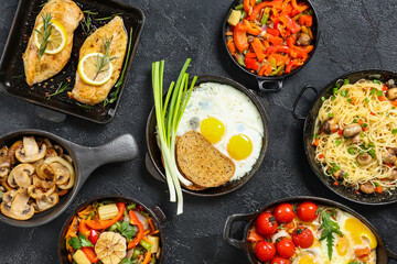 Frying pans with different dishes on dark background