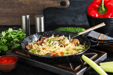 Frying pan with tasty pasta, mushrooms and sauce on dark table