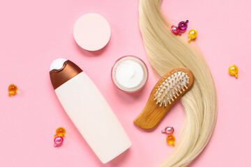 Blonde strand with jar of hair mask, brush and shampoo on pink background