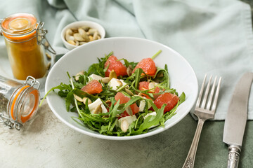 Bowl with healthy vegetable salad, napkin, spices and cutlery on grey grunge background