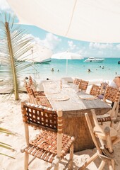 caribbean beach club wooden table setting with turquoise ocean View – tropical island luxury dining concept