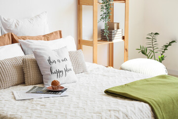 Big comfortable bed with muffin and many pillows in interior of bedroom
