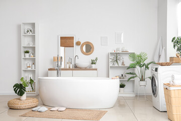 Interior of bathroom with bathtub, washing machine and wicker mat