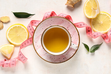 Composition with cup of diet tea, lemon and measuring tape on light background. Weight loss concept