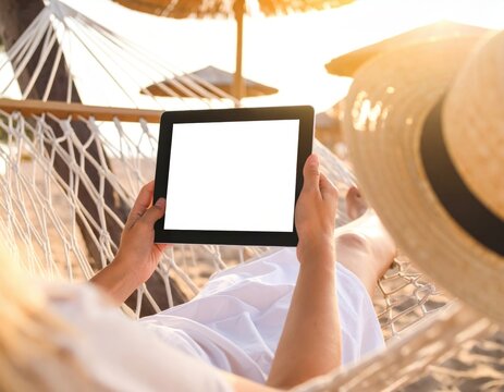 Woman Relaxing On Beach Hammock Using Tablet