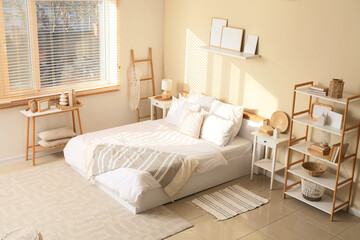 Cozy bed, shelving unit and frames in interior of bedroom