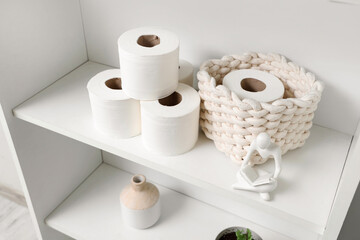 Shelving unit with rolls of toilet paper and decor in stylish restroom, closeup