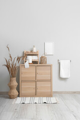 Interior of stylish restroom with wooden cabinet, towel and rolls of toilet paper