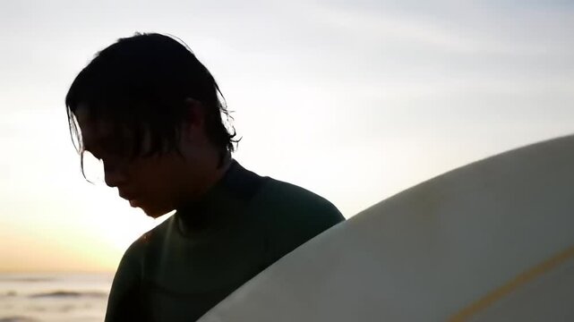 Silhouette of a surfer at sunrise