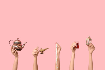 Female hands with Turkish tea, prayer beads and lantern on pink background