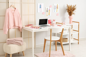 Interior of fashion designer's office with workplace, folding screen and shelf unit